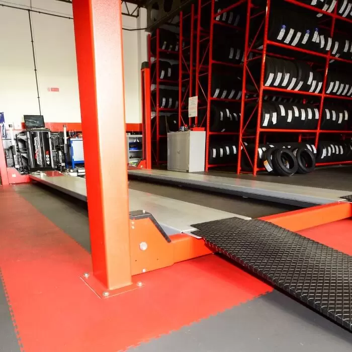 Red and dark grey garage floor tiles around ramps in a National Tyres commercial garage