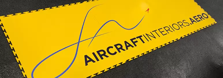 Aircraft Interiors branding on Yellow Ecotile logo tiles