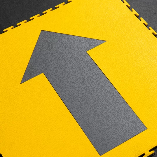 Directional arrow floor marking on Ecotile floor tile yellow