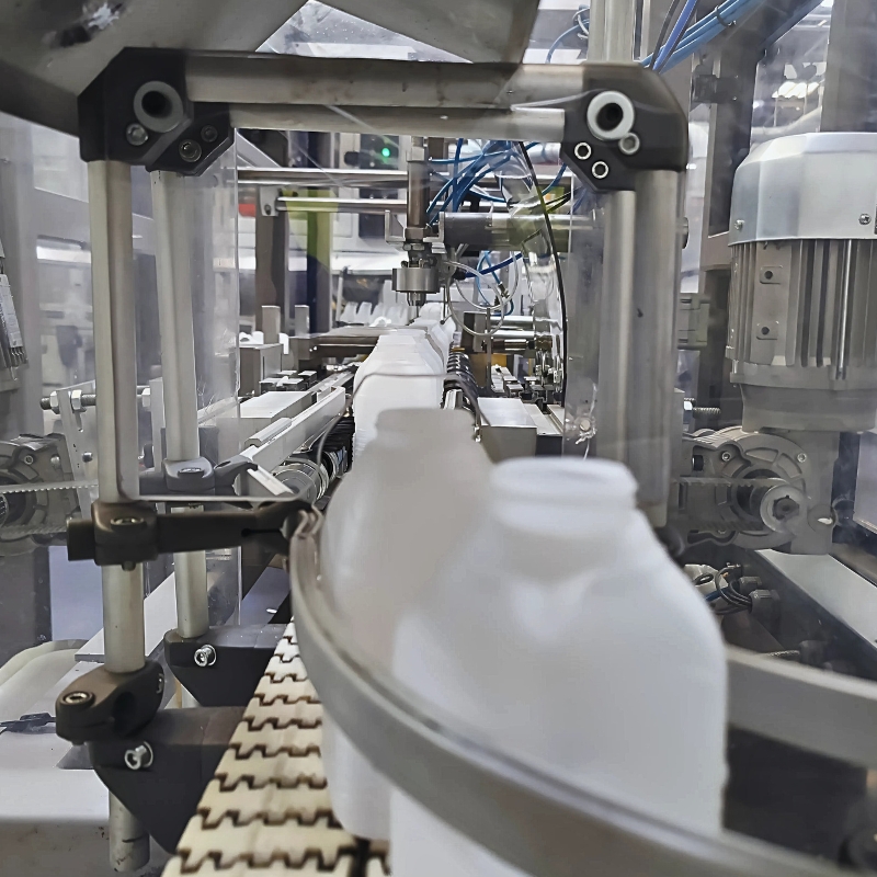 Blasgeformte Milchflaschen auf einem Produktionsförderband, wobei der Unterboden mit blauen „ecotile“-Industriebodenfliesen bedeckt ist