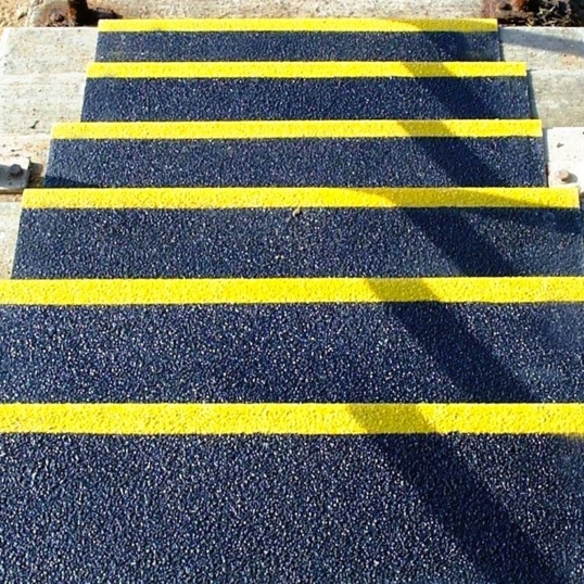 „Suregrip“-Treppenstufenbeläge auf den Außentreppen, die das Treppenhaus hinunterführen, in Schwarz mit gelben Kanten an jeder Stufe
