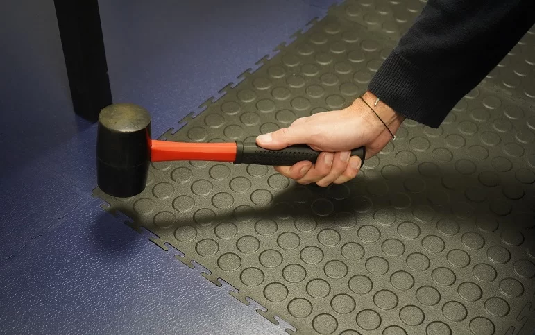 tapping an ecotile interlocking anti-fatigue floor tile into place with a mallet