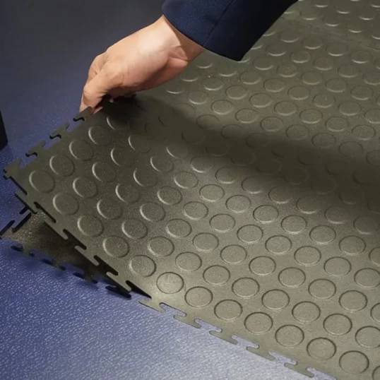 Image showing Ecotile's anti-fatigue version being peeled and removed from the floor, showing it's flexibility