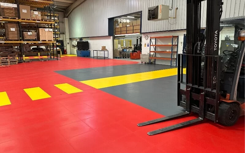 Micro Mesh warehouse, with a Toyota fork lioft truck on bold red and graphite ecotile industrial floor tiles, with a yellow safe walkway
