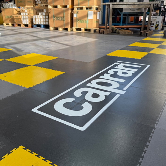 Utilisation des logos et revêtements de sol Ecotile à l'entrée du hall de l'entrepôt industriel de Caprari