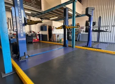 Ecotile graphite and blue tiles in car lift bay, with yellow ramps to signify safety markings