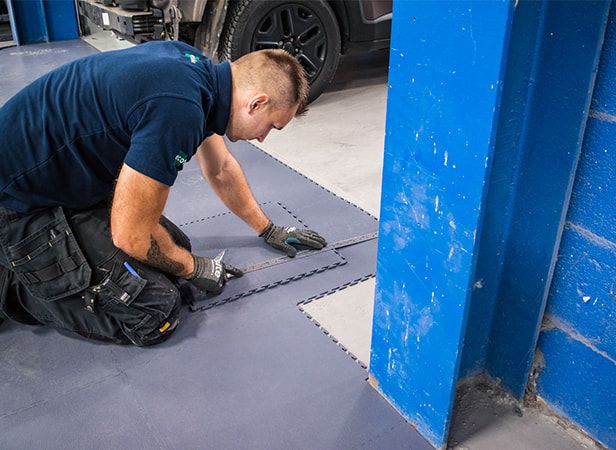 Man Installing Dark Grey Ecotile Workshop Flooring in A Commercial Garage