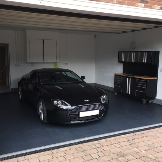 Une photo du revêtement de sol gris foncé d'Ecotile dans un garage, avec une Aston Martin