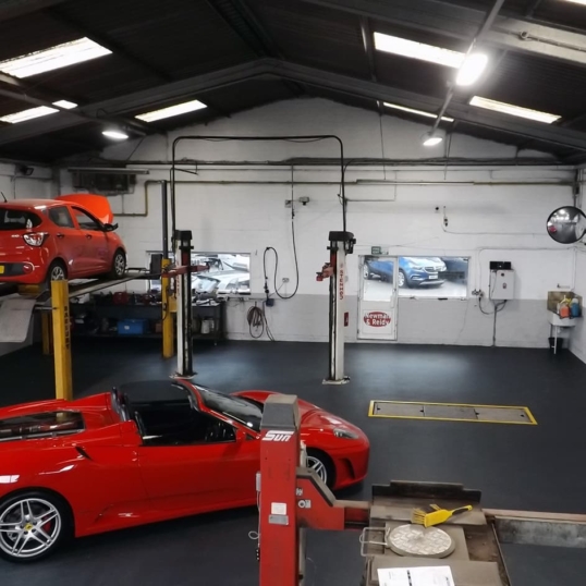 Automotive workshop with ferrari and vehicle lift ramps on flooring