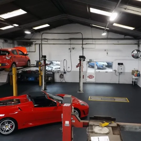 Automotive workshop with ferrari and vehicle lift ramps on flooring