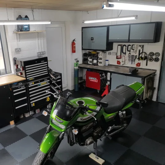 An image of a green motorcycle on PVC garage flooring tiles in dark grey and black pattern