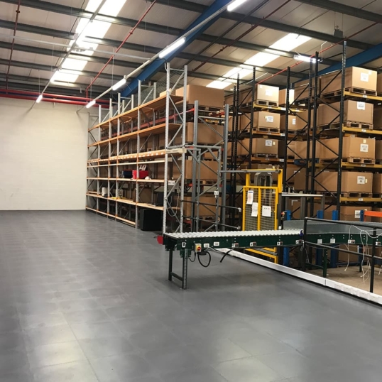 Image showing a warehouse with an automated conveyor belt, on a dark grey floor
