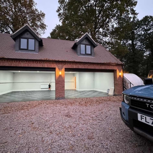 Une photo montrant, en arrière-plan, un garage pour deux voitures avec un nouveau revêtement de sol