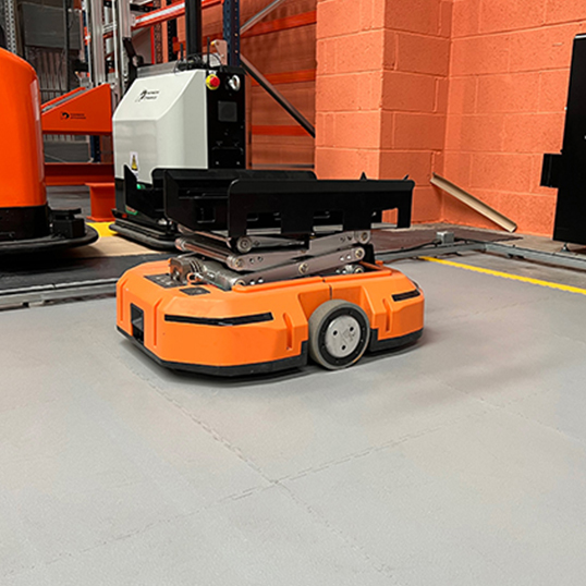 Image of an orange automated warehouse robot on light grey flooring