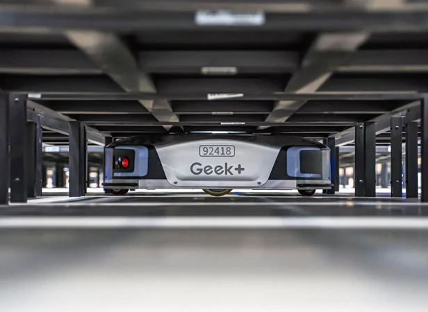 Geek+ robot under warehouse shelving at Yunex logistics